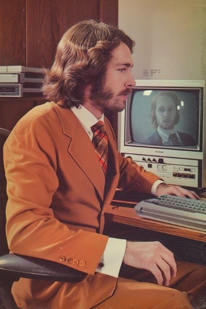 A professional setting with a mid-aged male recruiter, looking engaged and focused, sitting at his desk. One screen shows a video call in progress with a candidate, symbolizing the transition from traditional to virtual recruitment methods. His expression is one of attentiveness, highlighting the importance of technology in modern recruitment practices.