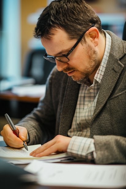A senior male HR manager, appearing meticulous and focused, drafting an appointment letter at his office desk. The environment is professional and well-organized, emphasizing the careful preparation of an official employment letter.