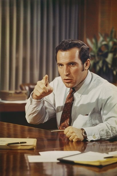 A male team leader, looking authoritative and supportive, leading a small team meeting in a sleek conference room. He's actively demonstrating leadership qualities and reliability, highlighting the traits employers look for in a professional setting.